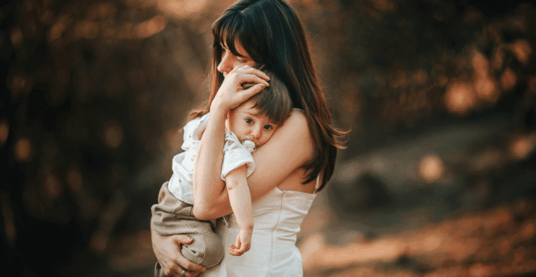 Uma mãe com um filho nos braços o abraçando de forma carinhosa.