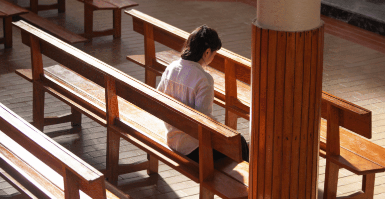 Uma mulher dentro de uma igreja onde os bancos estão vazios.