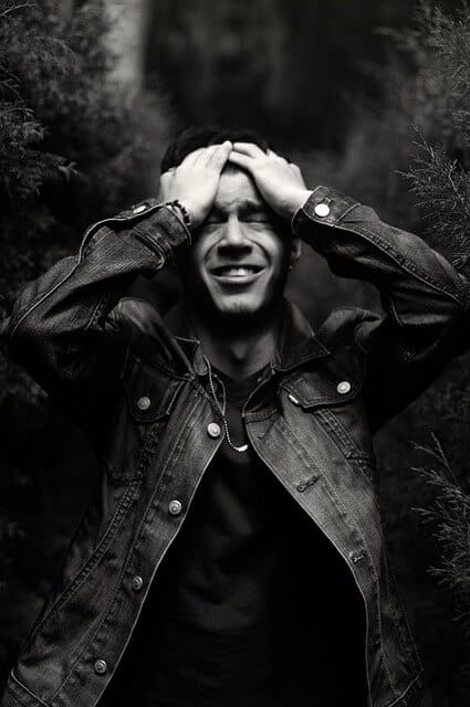 Um homem com expressão de frustração em um cenário em tons escuros